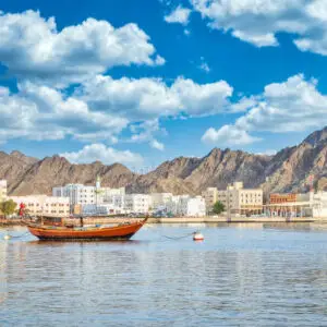 Old Sailboat anchored at Muttrah Corniche. The the old city and mountains in the background. From Muscat, Oman.