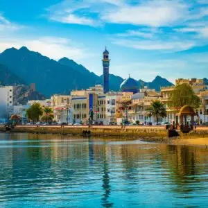 Landscape view of the ancient buildings stretches along the harbor overlooks mountainous rocky formations, Muscat, Oman - December 02, 2018